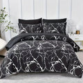 Black and white marble patterned bedding set on a bed with pillows against a white paneled wall.